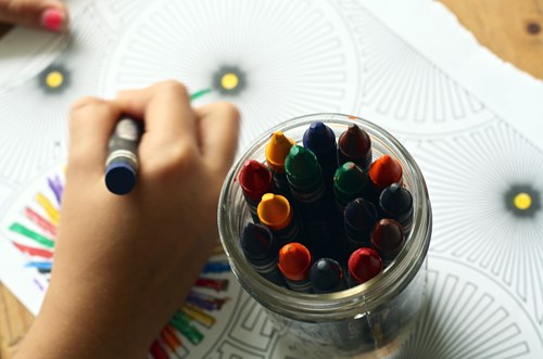 little girl hand holding a crayon coloring a page